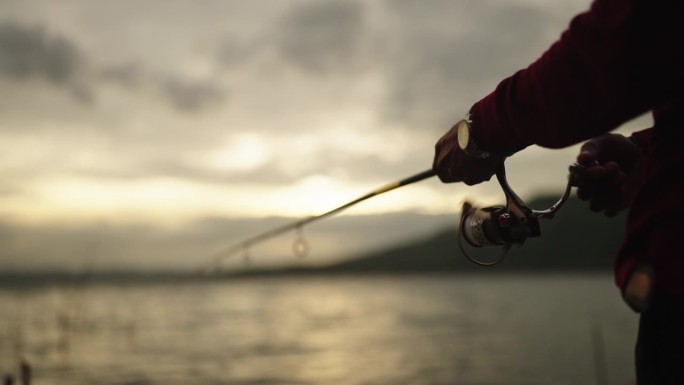 夕阳下渔夫手持鱼竿，享受着钓鱼的乐趣