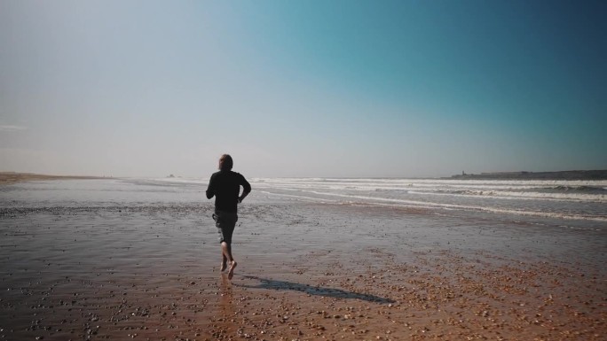 一个人沿着海岸线在沙滩上慢跑