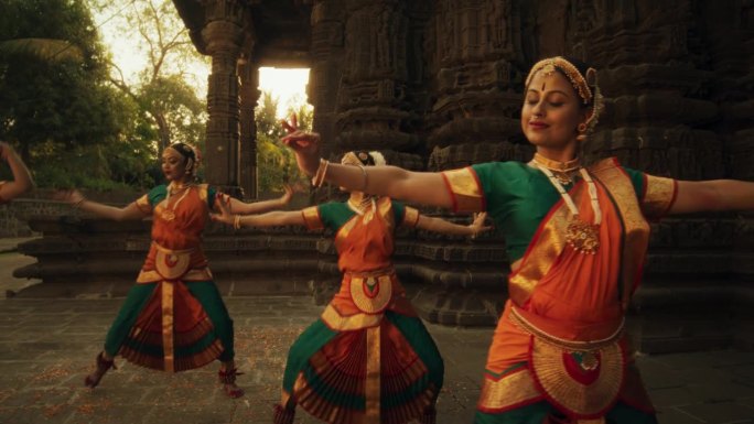 富于表现力的年轻女性在庙里跳民间舞蹈编舞的肖像。印度妇女穿着色彩鲜艳的传统服装，美丽而迅速地表演巴拉