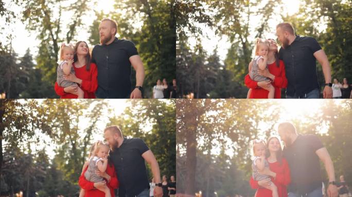 幸福迷人的年轻妈妈和爸爸抱着甜蜜的女婴女儿在公园散步，笑，拥抱，享受闲暇时间，亲密的家庭关系