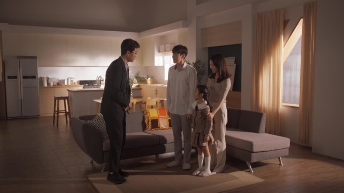 专业房地产经纪人向一个小家庭展示明亮的新公寓。韩国年轻夫妇成为房主，与房地产经纪人达成协议，对他们的