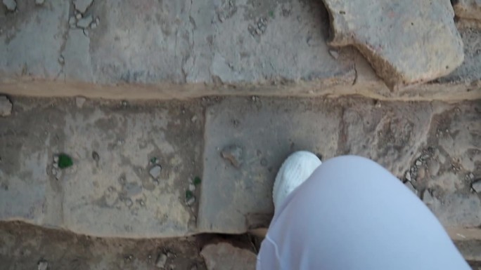 穿着白色运动鞋的双腿走上古老的石阶。从上面看。
