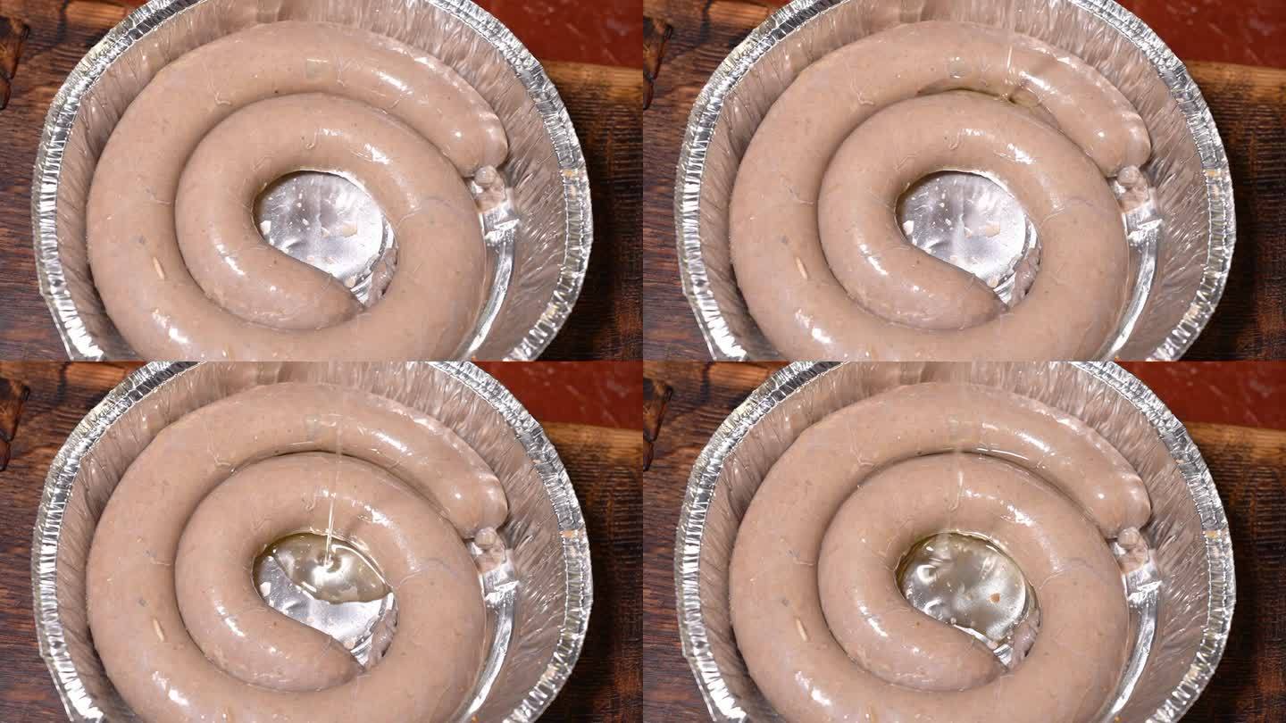 自制香肠在锡箔盘上螺旋形，倒入葵花籽油