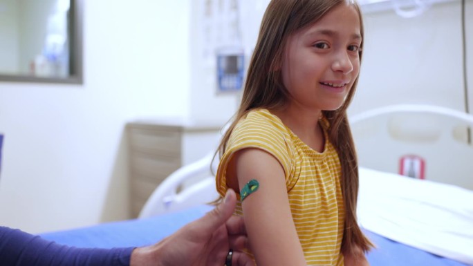 护士将创可贴贴在刚接种疫苗的女孩身上