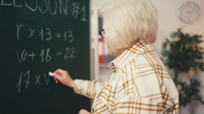 高级女数学老师在黑板上写方程式，在教一课