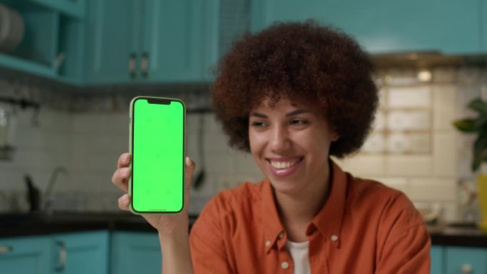 钱落在手持绿屏手机的黑人妇女身上。通过手机申请获得现金头奖。