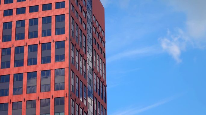 红色高大的办公楼，外墙白云与蓝色干净的天空背景，塔，窗户，城市景观，晴天，静态拍摄，特写，延时，透视