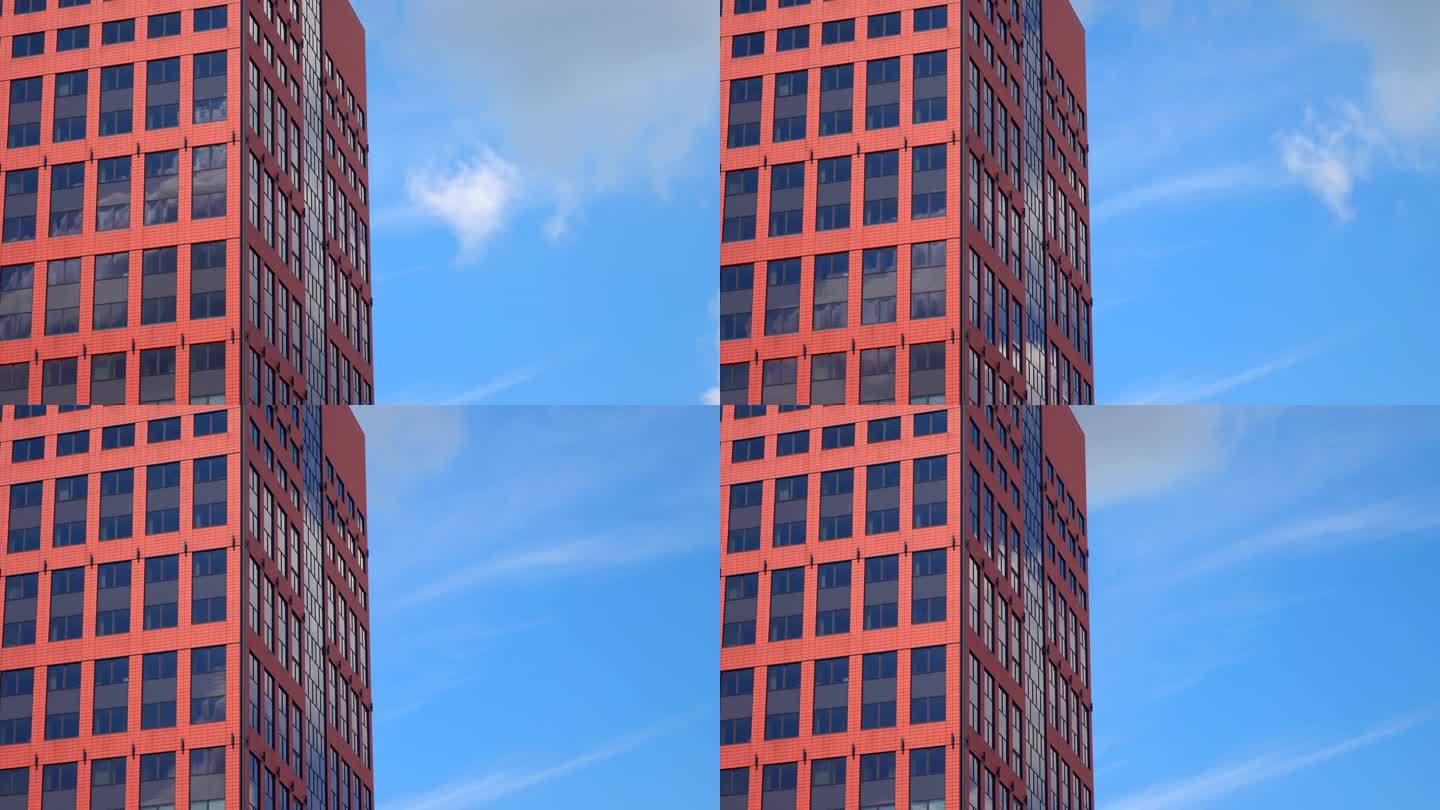 红色高大的办公楼，外墙白云与蓝色干净的天空背景，塔，窗户，城市景观，晴天，静态拍摄，特写，延时，透视