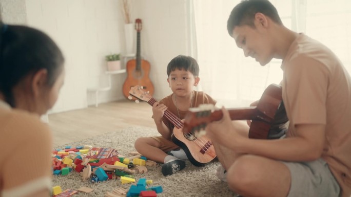 快乐的亚洲父子通过音乐联系在一起，在家里一起弹吉他
