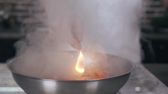 厨师正在往锅里倒油，里面有樱桃，火焰，近距离