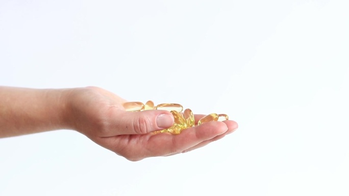 女性手里拿着金色鱼油欧米伽3胶囊