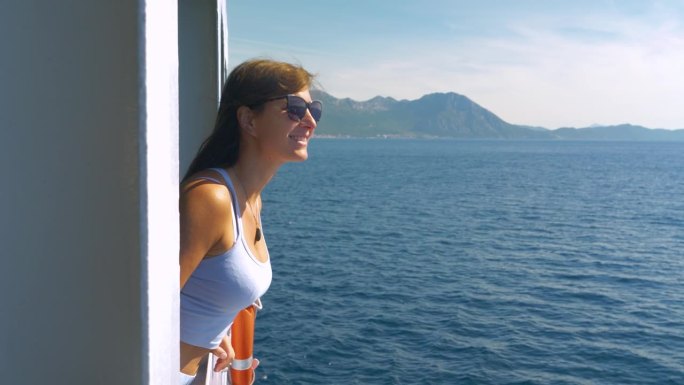 在前往克罗地亚岛屿的渡轮上，微笑的女士被海风吹着她的头发