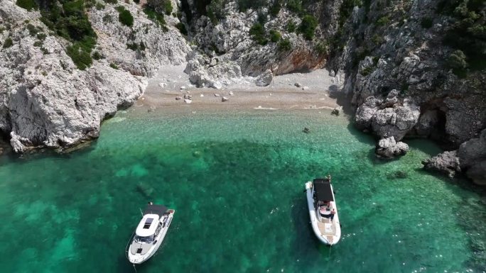 航拍无人机的帆船停泊在清澈的水岩石海岸线