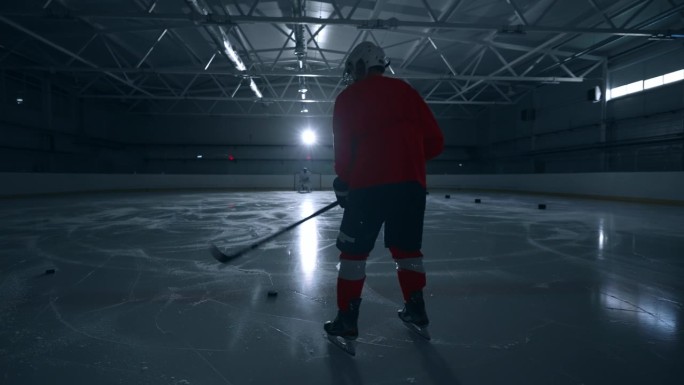 一段动感十足的视频显示，一名身穿红色运动衫的冰球运动员在冰上快速移动，巧妙地避开障碍物并得分