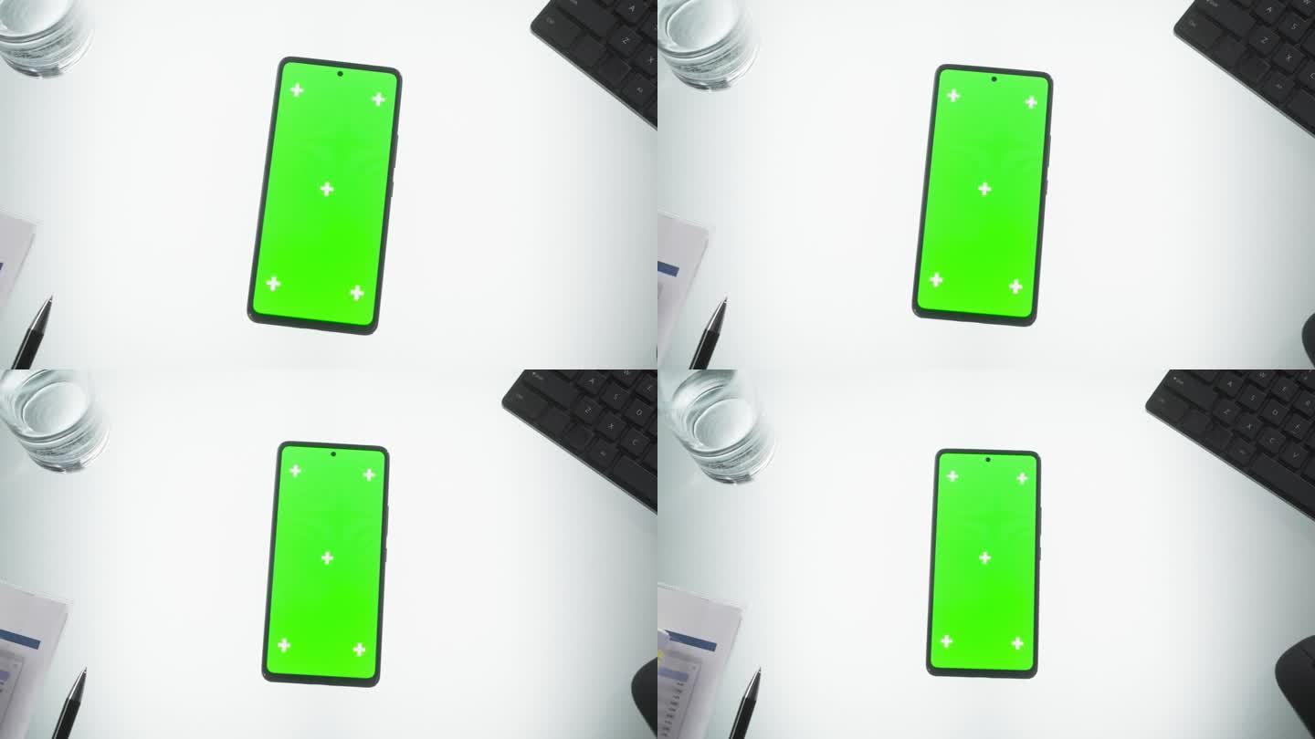 智能手机模拟绿色屏幕Chromakey显示与运动跟踪占位符。放大旋转镜头视图的手机设备在办公桌上的键