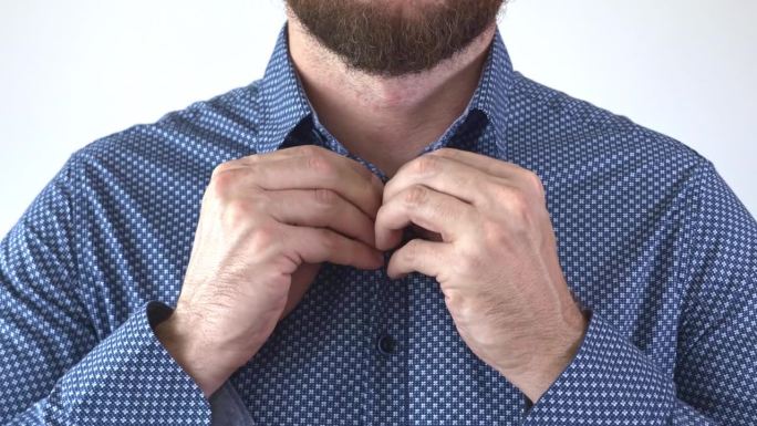 蓝色衬衫的扣子扣不全。