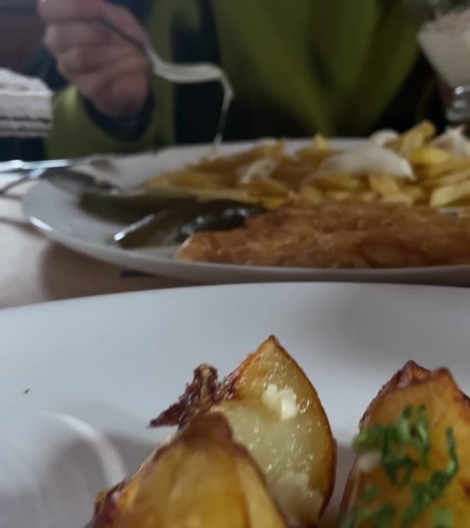 靠近盘子里的食物在餐馆里吃土豆的女人