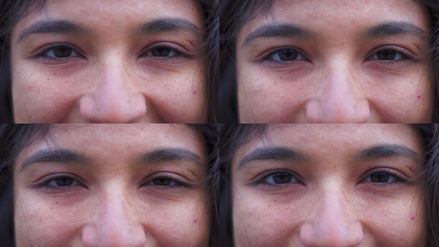 微距拍摄的印度妇女眼睛看着相机。自信的年轻女子的眼睛，脸上有雀斑，皮肤健康。微笑的女孩的眼睛特写，快
