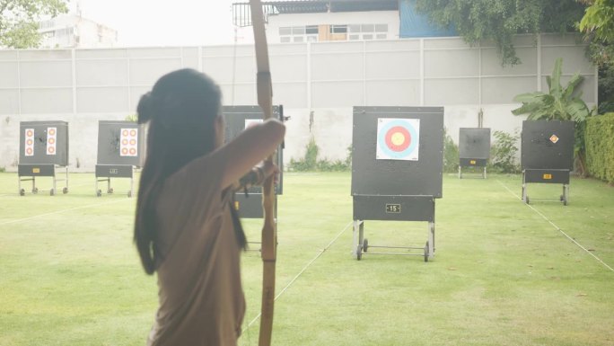 迷人的亚洲女性在靶场练习射箭。射箭。