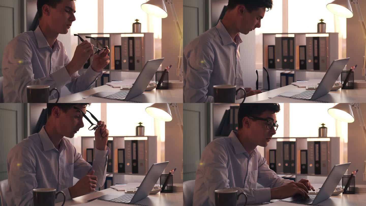 商人一边用笔记本电脑打字，一边擦眼镜