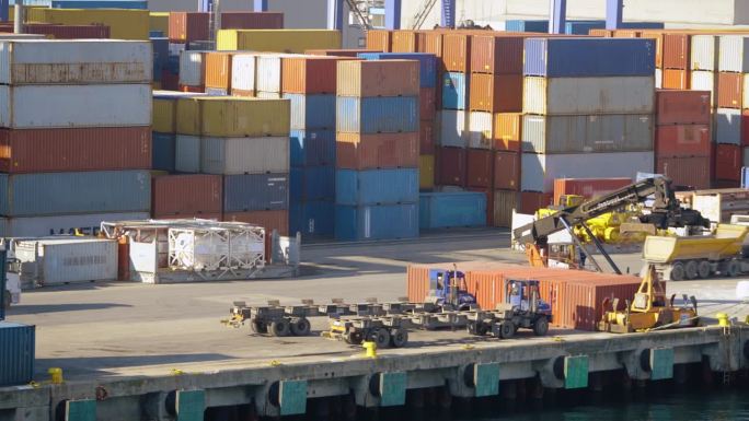 4K画面显示卡车和货物拖车经过集装箱。彩色集装箱堆放在商业港口库存视频。