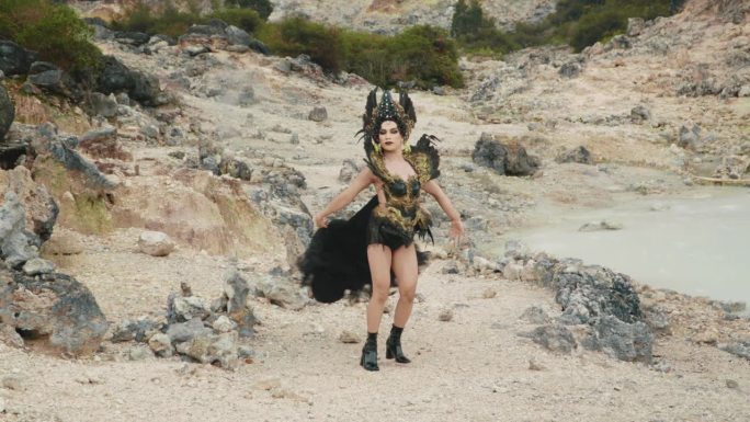一个穿着黑色服装的女巫走在一个充满石灰岩的山谷里