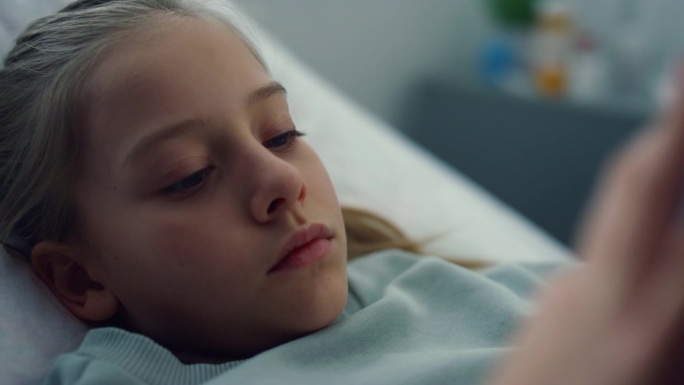 在诊所里，心烦意乱的孩子抱着最喜欢的毛绒玩具躺在床上。