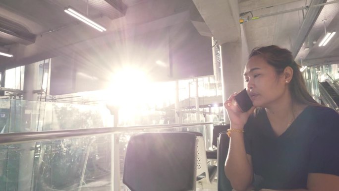 一名亚洲妇女正在和她的亲戚打电话，他们将在凌晨时分在机场下机。
