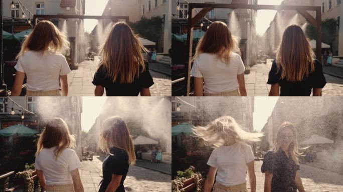 两个戴着圆形太阳镜的美丽快乐的年轻女子穿过街头喷雾，转身对着镜头微笑。