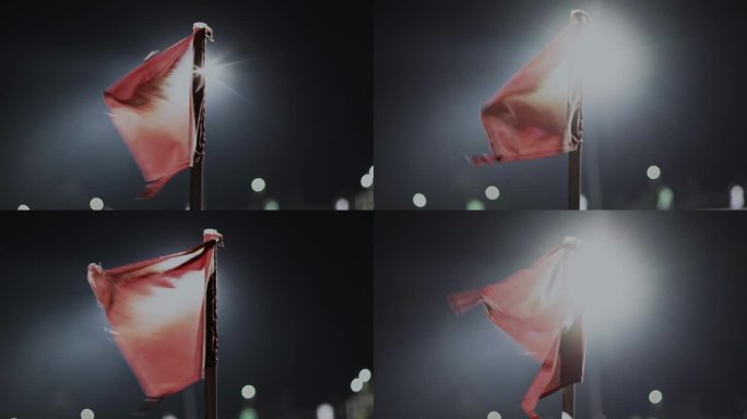 在夜晚的足球比赛中，角球区红旗迎风飘扬。关闭了。英式足球比赛。体育场聚光灯下的照明弹和灯光。体育的概