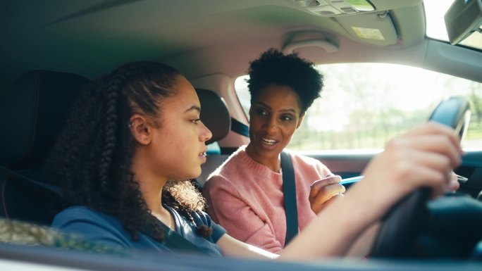 十几岁的女孩在车里上女教练或家长的驾驶课