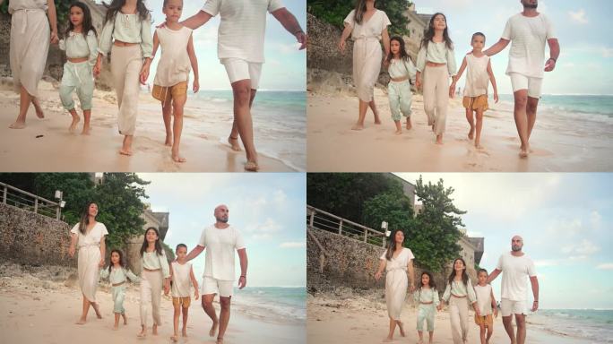 一男一女带着孩子在海滩和海水边散步的快乐家庭。热带旅游的小女孩和男孩在岸边放松与妈妈和爸爸。健康美与