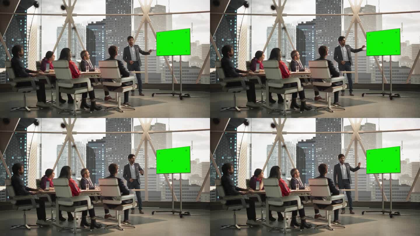 多样化的印度办公室会议室:年轻的CEO为企业家做演讲，用绿色屏幕模拟显示的电视讲话。商人谈论金融市场