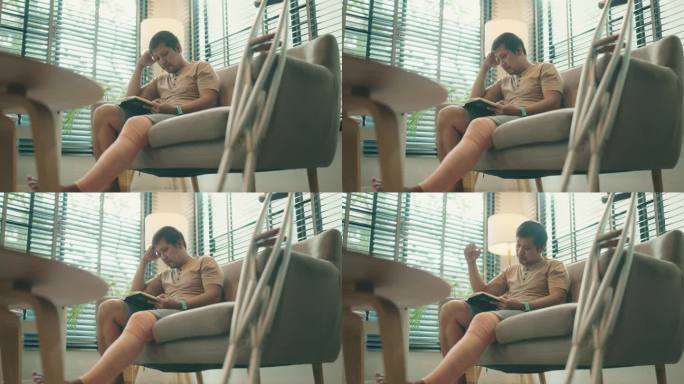 亚洲英俊的残疾男子坐在家里客厅的沙发上看书的肖像。