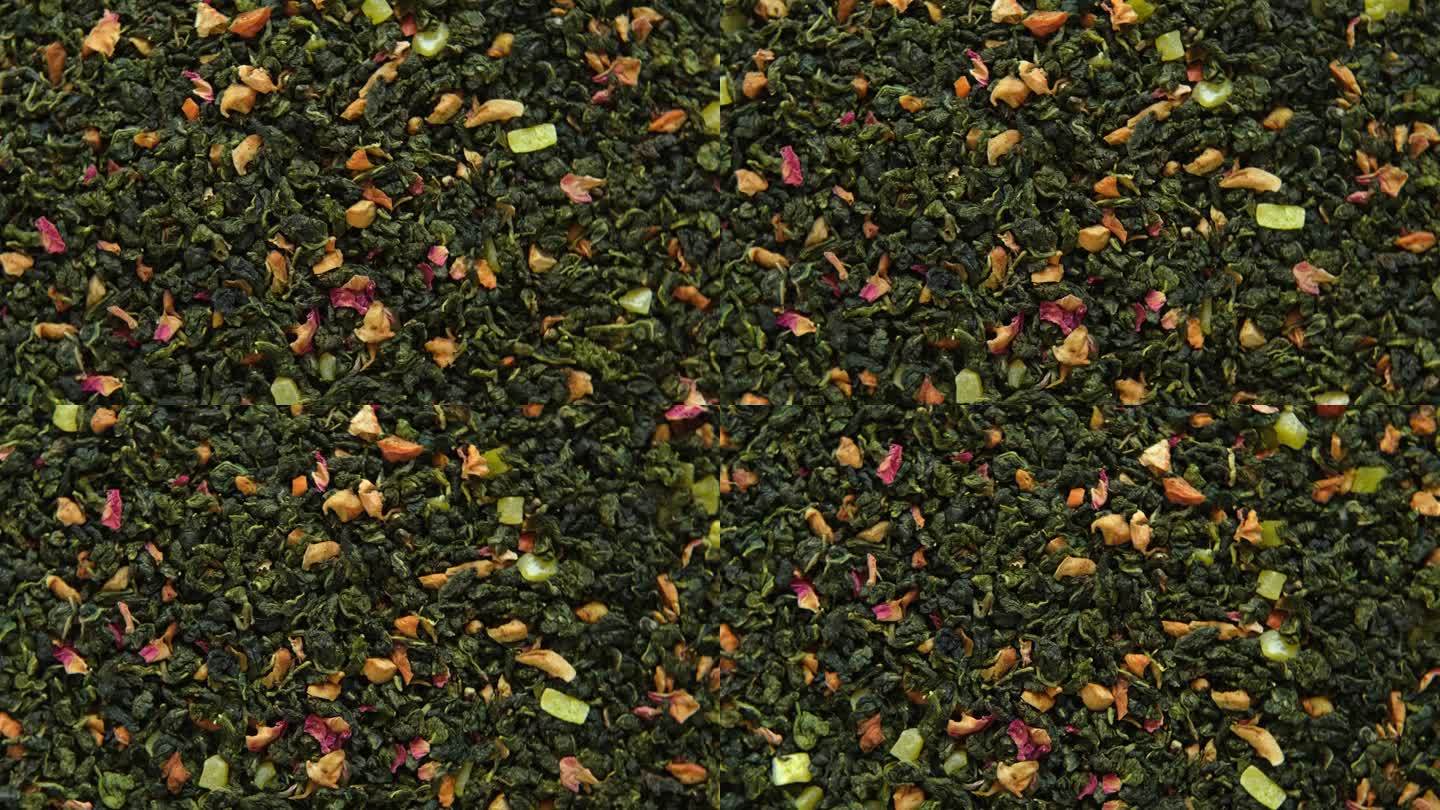 散叶芒果菠萝水果茶壁纸。混合红茶和绿茶干茶叶。特写，微距。前视图。纹理。干茶在旋转。摘要食品和饮料的