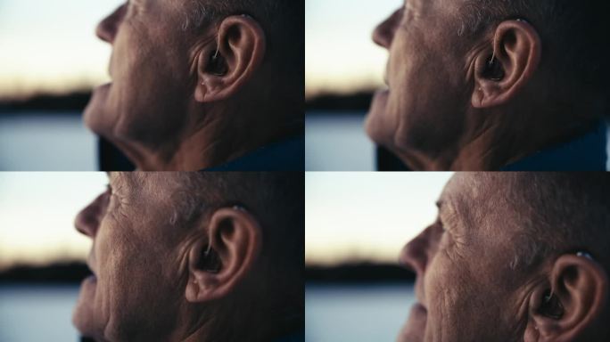 一位戴着助听器的老人在冬日黄昏享受着新鲜的空气