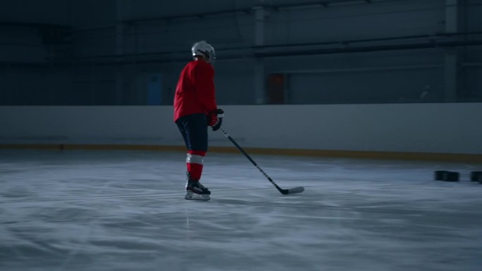 一名身穿红色球衣的冰球运动员在黑暗的冰场上展示自己的技术，同时避开障碍，轻松得分