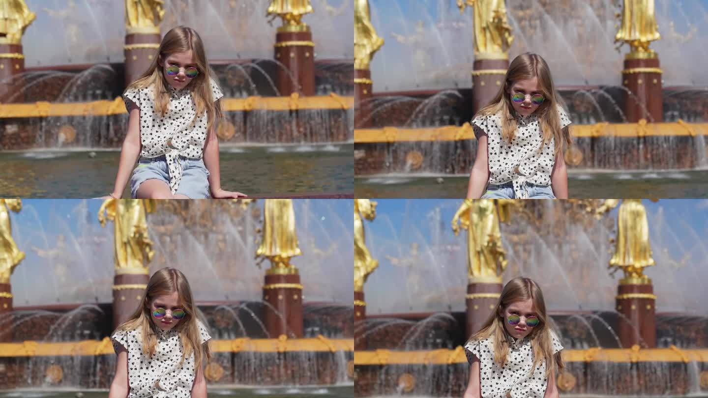 一个戴着墨镜站在人民友谊喷泉前的少女。
