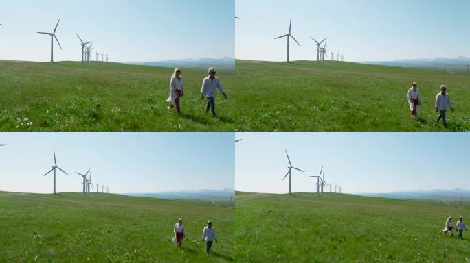 一对老年夫妇走进风力涡轮机下的草地
