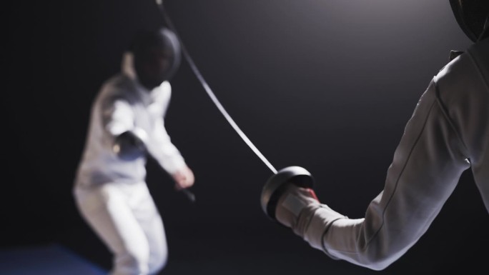 后视图两名职业击剑运动员在比赛中穿着防护装备碰撞花剑