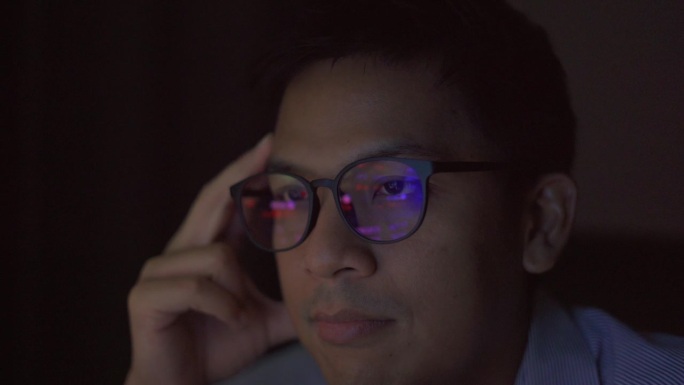 一个亚洲商人，晚上在电脑前分析数据，情绪紧张。