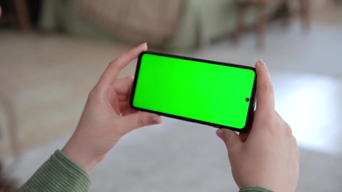 近距离观察女性的手使用水平智能手机与关键的绿色屏幕。色度键模拟流媒体服务的应用。在网上看视频。有选择