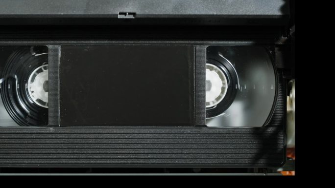旧录像机里面的特写，VHS。复古播放器在霓虹灯红色，老式录像带广播，录音带。