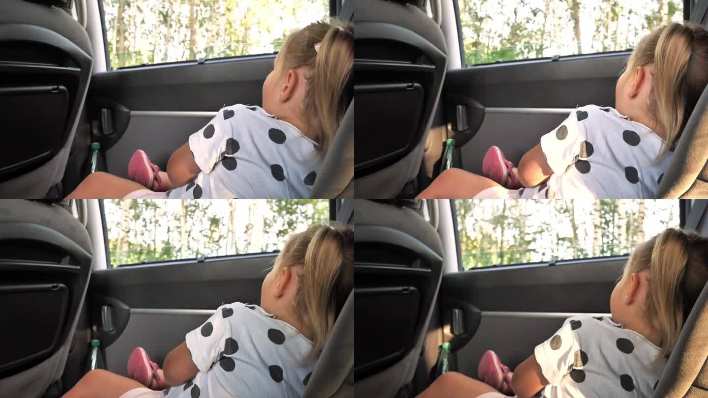 一个小孩坐了很长时间的车，很累，他望着窗外打呵欠。在一次家庭驾车旅行中，一英里女孩望向窗外。家庭驾车