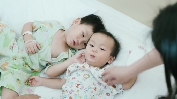 一个亚洲家庭在医院安慰和玩耍两个生病的孩子。健康的生活方式。流感病毒A。
