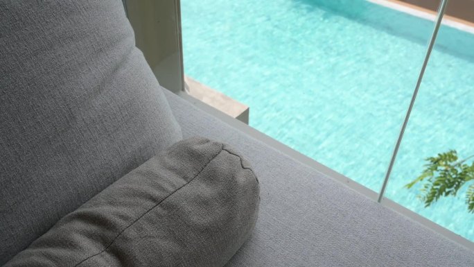 灰色的枕头放在床上，游泳池的景色和慢动作的水波