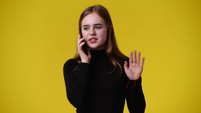 一个女孩用手机的4k视频，黄色背景。
