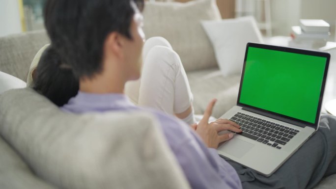 这是一对韩国夫妇在舒适的公寓里一起度过的时光，他们在一台绿屏模拟显示器的笔记本电脑上上网和搜索信息