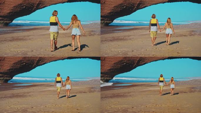 一对幸福的夫妇在沙滩上散步，手牵着手走向红砂岩天然拱门