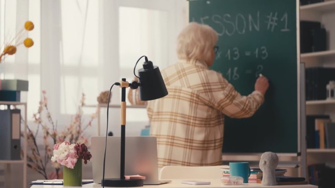 高级女教师在黑板上写数学方程式，讲解任务